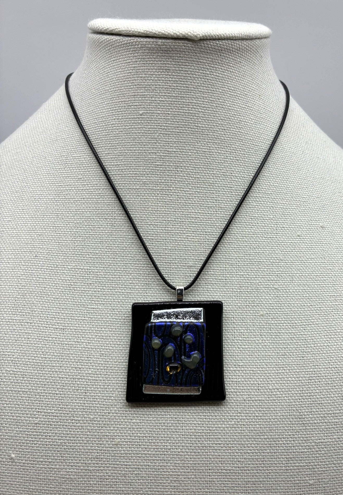 Jewelry -Offset square of black raised glass with dichroic silver and blue and black swirl glass.