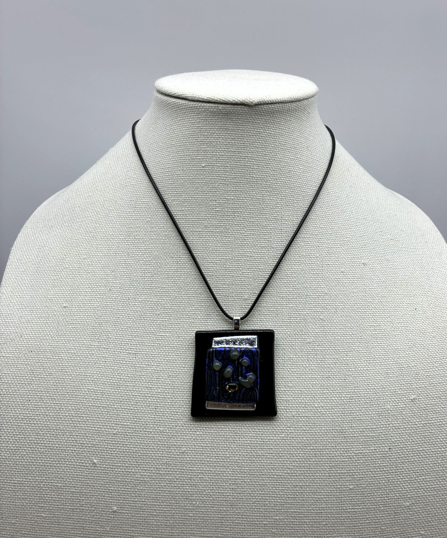 Jewelry -Offset square of black raised glass with dichroic silver and blue and black swirl glass.