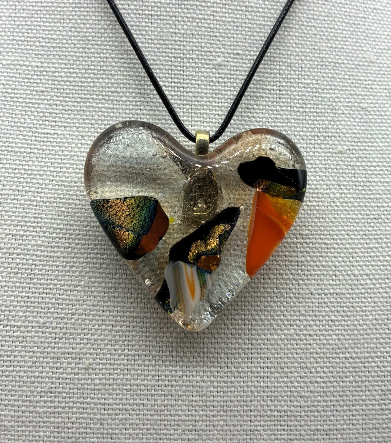 Jewelry -Clear glass heart with colors of orange, gold, black and white glass captured within Heart.