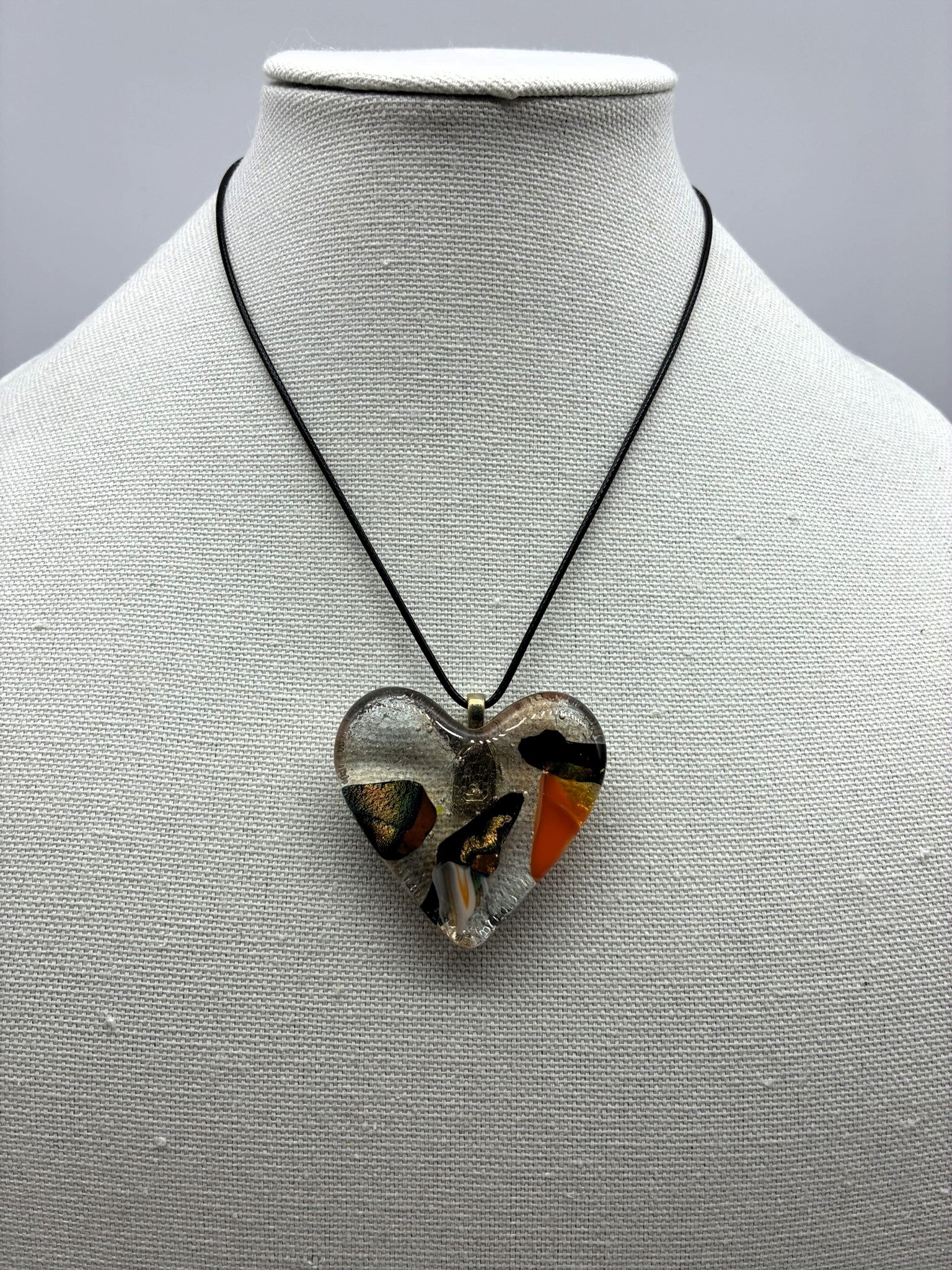 Jewelry -Clear glass heart with colors of orange, gold, black and white glass captured within Heart.