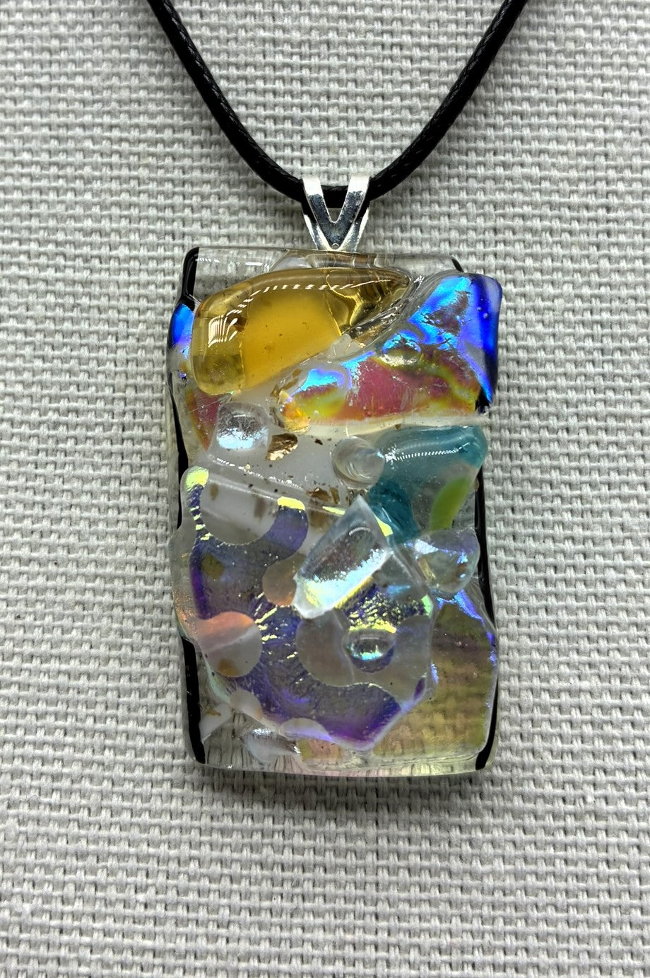 Jewelry - Small clear glass rectangle holding numerous pieces of cut and dichroic glass